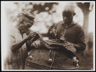 2 Males Sewing a skin to the Top of a Drum