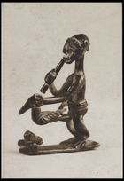 1 figurine blowing a pipe and holding a bird, standing in profile