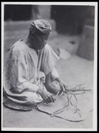 1 male dressed in a tunic and head scarf plaiting fibres