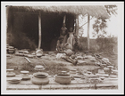 1 female and 2 children standing among a large collection of pots