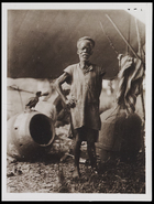 1 male standing in front of the body of a drum under a shelter with upturned drum body upside down