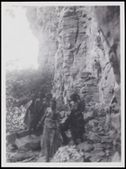 2 females in the foreground, 3 others behind walking beside a rockface