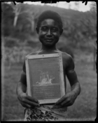Young boy, called Vailala, wearing tradecloth wrap, probably a student at the Mission School, holding a slate with a drawing of the London Missionary Society boat 