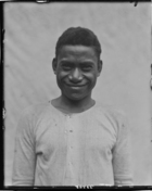 Young boy called Anaderea, possibly a servant, standing against a white cloth backdrop wearing a European shirt
