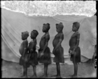Five young girls with elaborately shaved heads, standing in a row in front of a white cloth backdrop