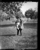 Small girl holding a cat, standing in grounds of London Missionary Society Mission House