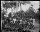 man and woman South Seas teachers of the London Missionary Society, sitting posed with large group of women and children, some in European clothing