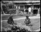 two men sitting repairing a fishing net