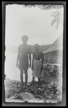 A man and a boy, both with clothes on, stand on Rubiana Lagoon, New Georgia Island; full face.