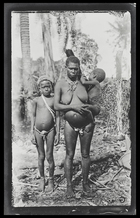 A woman holding a baby standing next to a child; on Kulumbangra Island, a large volcanic island near Gizo.