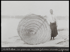 man standing by large wicker fishing trap