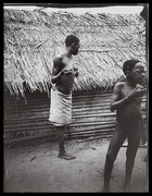 woman and young boy standing in front of thatched hut