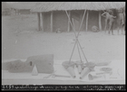 blacksmiths tools laid out on white cloth, huts in background