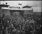 Liberated prisoners in the Mauthausen concentration camp near Linz, Austria, give rousing welcome to Cavalrymen of the 11th Armored Division. The banner across the wall was made by Spanish Loyalist prisoners., 05/06/1945