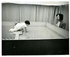 Black and white photograph of infant crawling on visual cliff checker board
