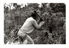 Black and White photograph of man chopping down vegetation