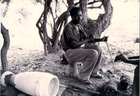 Black and White photograph of a man with a drum lying next to him