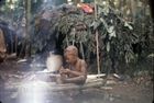 A child, Ngbanda, sat on a raised low wooden platform made of logs and outside the dome-shaped shelters in a settlement.