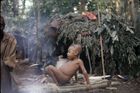 A child, Ngabanda, sat reclining on a low raised wooden platform made of logs.