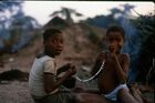 Two young girls, Metimbo and Mongo, sat on the floor and stringing black and white beads together to make a necklace.