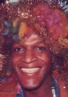 Clour photo of Marsha P. Johnson smiling and wearing a multi-coloured wig.